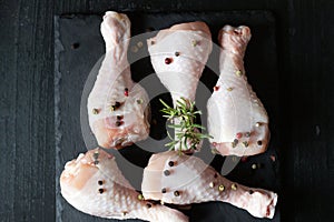 Raw chicken legs on slate plate. on wooden background. closeup