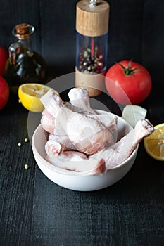 Raw chicken legs on slate plate. on wooden background. closeup