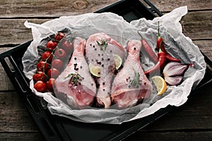 raw chicken legs with spices and fresh vegetables on paper