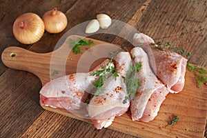 Raw chicken legs on wooden board.