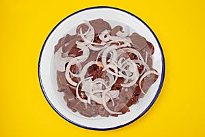 Raw chicken liver meat with onion on white dish