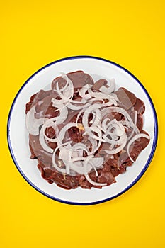 Raw chicken liver meat with onion on white dish