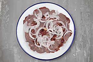 Raw chicken liver meat with onion on white dish