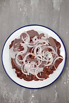 Raw chicken liver meat with onion on white dish
