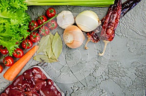 Raw chicken liver, vegetables and spices for making pate on a textured concrete-gray background