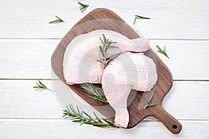 Raw chicken meat with rosemary / fresh raw chicken leg fillet on wooden cutting board background