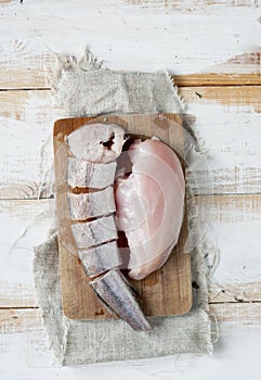 Raw chicken meat with sliced fish hake on the chalkboard,