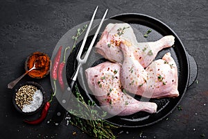 Raw chicken quarters, legs in a pan on a dark background