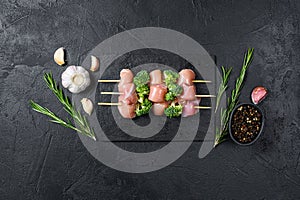 Raw chicken shish kebab with broccoli, Barbecue. Black background. Top view