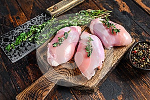 Raw Chicken skinless thigh fillet on a wooden cutting board. Black background. Top view