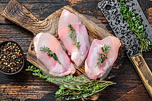 Raw Chicken skinless thigh fillet on a wooden cutting board. Black background. Top view