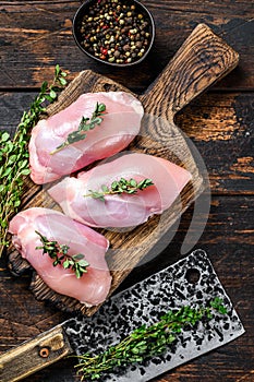 Raw Chicken skinless thigh fillet on a wooden cutting board. Black background. Top view