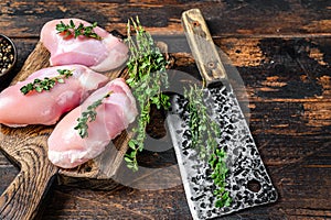 Raw Chicken skinless thigh fillet on a wooden cutting board. Black background. Top view. Copy space