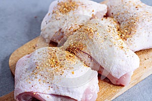 Raw chicken thigh with herbs on cutting board on grey table