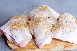 Raw chicken thigh with herbs on cutting board on grey table