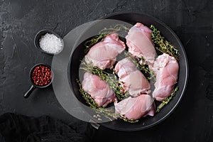 Raw chicken thighs on frying pan on black backgroundtop view