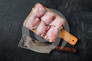 Raw chicken thighs with meat cleaver, on black background, top view