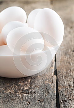 Raw chicken white eggs in white bowl on wooden background