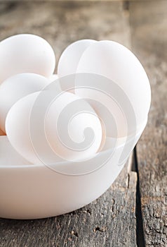 Raw chicken white eggs in white bowl on wooden background