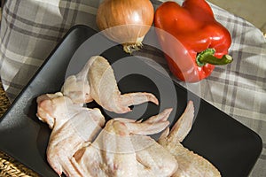 Raw chicken wings on black with onion and red paprika