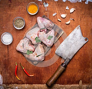 Raw chicken wings a cutting board with red pepper herb herbs garlic meat cleaver on rustic wooden background top view