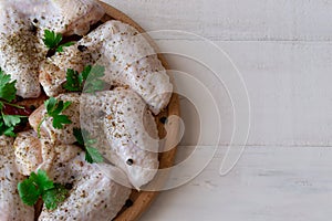 Raw chicken wings with ingredients for cooking on wooden cutting board over white wooden background.Top view