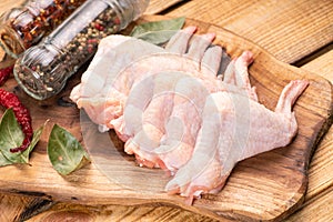 Raw chicken wings on a kitchen board with red hot peppers and spices. Raw chicken meat.Raw chicken wings on cutting board