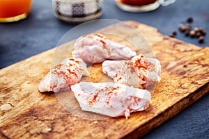 Raw chicken wings with spices on a wooden cutting board