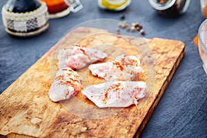 Raw chicken wings with spices on a wooden cutting board