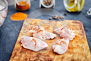 Raw chicken wings with spices on a wooden cutting board