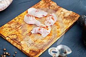 Raw chicken wings with spices on a wooden cutting board