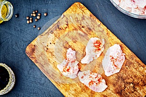 Raw chicken wings with spices on a wooden cutting board