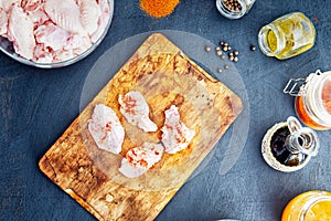 Raw chicken wings with spices on a wooden cutting board