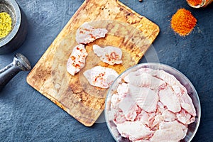 Raw chicken wings with spices on a wooden cutting board