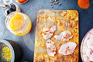 Raw chicken wings with spices on a wooden cutting board