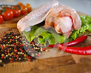 Raw chicken wings on wooden round board on white background.