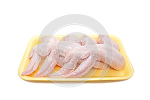 Raw Chicken wings in a yellow polystyrene container isolated on white background. Four fresh chicken parts for cooking. Side view.