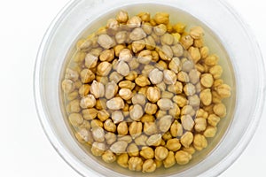 Raw chickpea drenched in water in a transparent bowl, prepared for cooking and future use, concept is healthy eating, horizontal