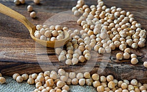 raw chickpeas in a wooden spoon on a rustic wooden cutting board close-up