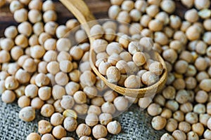 raw chickpeas in a wooden spoon on a rustic wooden cutting board close-up