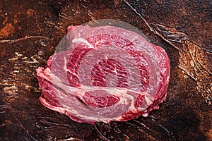 Raw Chuck eye roll beef steak on butcher table. Dark background. Top view