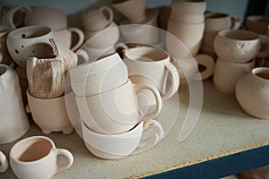 Raw clay cups stand on a shelf