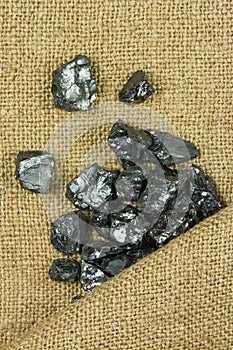 Raw coal on sack background