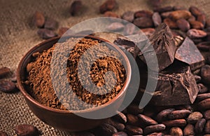 Raw cocoa beans, clay bowl with cocoa powder, chocolate on sack