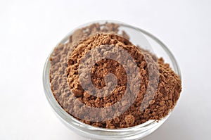 Raw cocoa Theobroma cacao powder in a glass bowl, isolated