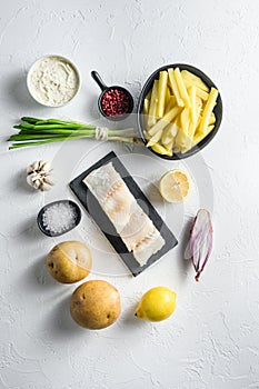 Raw cod fillet and other organic ingredients recipe fish and chips batter, potatoe, tartar sauce, lemon, capers , green herbs