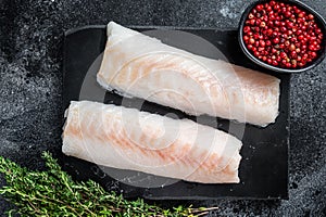 Raw cod loin fillet fish on marble board. Black background. Top view