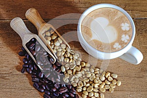 Raw coffee bean and roasters coffee bean in wood spoon and hot late art coffee