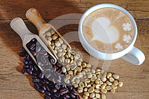 Raw coffee bean and roasters coffee bean in wood spoon and hot late art coffee photo
