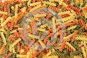 Raw colored pasta fusilli. Uncooked pastas background